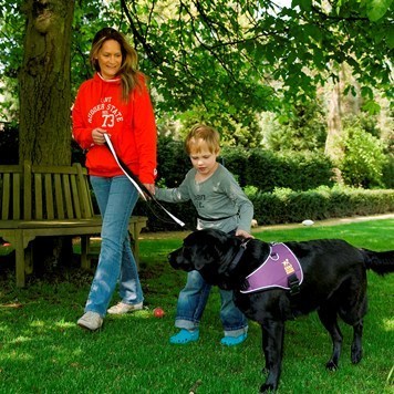 собака-поводырь на прогулке с ребёнком-аутистом под присмотром матери